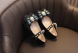 Dettaglio di scarpe da principessa nere glitterate con fiocco strass e cinturino perle