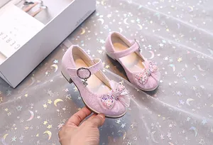 Détail de chaussures Mary Jane roses pailletées avec nœud en résille et flocon de neige