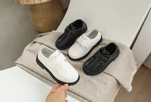 Detail view of boys' formal leather shoes in black and beige with hook-and-loop straps