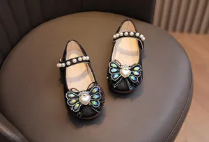 Dettaglio di scarpe Mary Jane glitter nere con fiocco di strass e cinturino di perle
