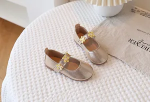 Detail of champagne gold Mary Jane shoes for girls with decorative yellow daisies