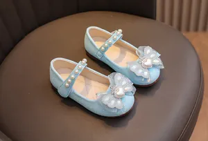 Dettaglio scarpa blu glitterata con cinturino di perle e fiocco in pizzo bimba