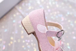 Détail de chaussure princesse rose pailletée avec talon bloc et pendentif nœud strass