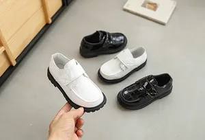 Detailed close-up of boy's embossed patent leather shoe with velcro strap and rubber sole