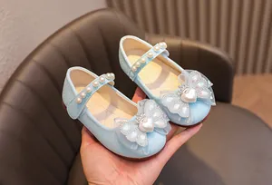 Dettaglio di scarpe da principessa glitter azzurre con fiocco e perla a cuore