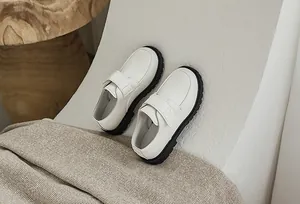 Detail of boys' beige leather dress shoes with black rubber sole and velcro strap closure