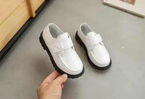 Detail of white boys dress shoe with embossed texture and velcro strap closure