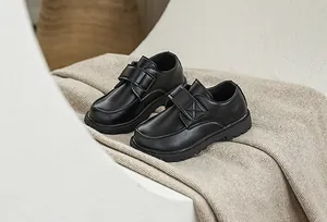 Detail of boys' black leather dress shoe featuring a convenient hook and loop strap