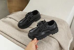Detail of children's black leather shoes featuring non-slip rubber soles and velcro straps