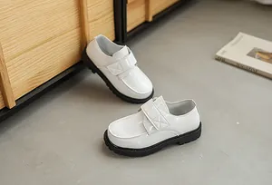 Detail of white crocodile pattern boy shoes with velcro strap and thick black rubber sole