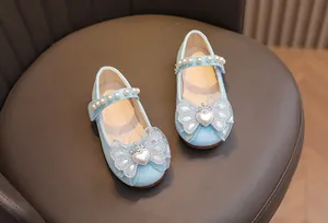 Dettaglio delle scarpe blu glitterate da bambina con cinturino di perle e fiocco