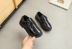 Detail of boys black patent leather loafers with crocodile texture and velcro straps