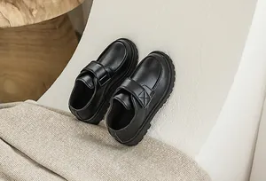 Detail of black boys' leather dress shoe with adjustable velcro strap and non-slip sole