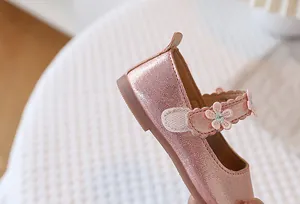 Detailed macro view of pink pearlescent Mary Jane girls shoes with 3D floral embroidery