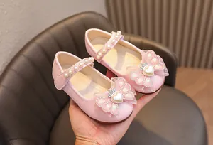Dettaglio scarpe Mary Jane rosa glitterate con cinturino di perle e fiocco corona
