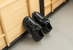 Detailed view of boys black loafers with crocodile texture and velcro closure