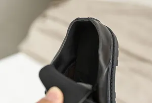 Detail of boys' black leather shoe featuring breathable mesh lining and padded heel support