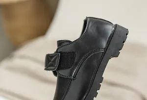 Detailed close-up of kids black leather formal shoes with Velcro strap and lug sole