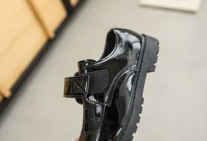 Detail of glossy black patent leather boys shoes with textured crocodile pattern