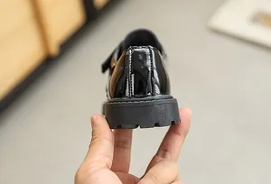 Detailed macro view of the glossy patent leather heel and non-slip rubber sole for boys shoes