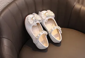 Dettaglio di scarpe da principessa glitterate con grande fiocco in pizzo e perla