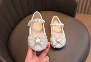 Dettaglio scarpe da principessa con fiocco, perla a cuore e corona di strass