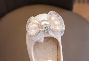 Dettaglio macro del fiocco in pizzo scintillante e perla a cuore sulle scarpe da principessa