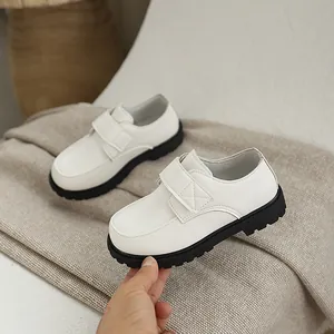 Classic white leather boy's school shoes with black chunky soles and velcro strap