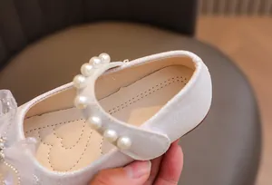Dettagli scarpa da principessa con perle, fiore in rete e finitura bianca lucida
