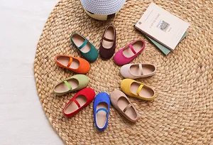 Top view of colorful kids Mary Jane flats in various candy colors on woven mat