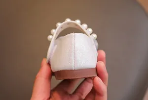 Dettaglio della texture glitter perlata e cinturino con perle su scarpe basse da bambina