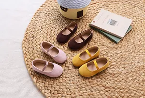 Three pairs of candy-colored suede girls' Mary Jane shoes on a woven straw mat