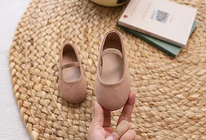 Detail of girls beige suede Mary Jane shoes with elastic strap on a woven mat