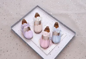 Detail von vier glitzernden Mary-Jane-Schuhen für Mädchen mit Blumen- und Perlendekor
