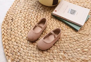 Detail of pink suede Mary Jane flat for girls with elastic strap on a woven mat