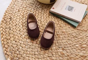 Close-up of brown suede Mary Jane shoes for girls on a rustic woven mat backdrop
