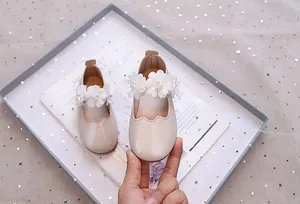 Detail von Chiffon-Blumen und Perlen auf beigen Prinzessinnen-Schuhen für kleine Mädchen