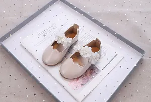 Detailansicht der perlmuttweißen Mary Jane Schuhe mit Tüllblumen und Wellenrand