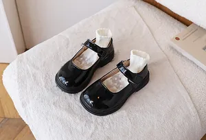 Detailed macro view of black patent leather girls Mary Jane shoes with ruffled white socks