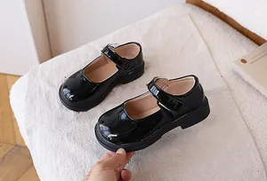 Detail of girls' black patent leather Mary Jane shoes with velcro strap and chunky sole