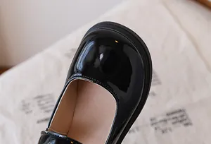 Detailed close-up of glossy black patent leather Mary Jane shoes with thick rubber soles