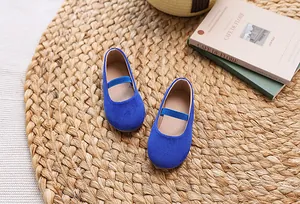 Macro shot of blue suede girls Mary Jane shoes with elastic strap on a woven mat