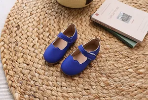 Detailansicht blauer Mary Jane Schuhe mit Wellenkante auf einer Strohmatte