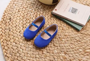 Detail of navy blue Mary Jane shoes for girls with elastic strap on a woven mat background