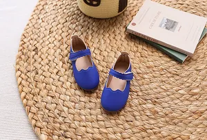 Detailansicht der dunkelblauen Mary Jane Mädchenschuhe mit Wellenriemen auf Strohmatte