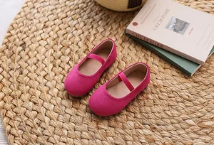 Detail of magenta suede Mary Jane shoes for girls on a natural straw mat background