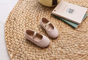 Detail of pink suede Mary Jane flat shoes for girls with elastic strap on a woven rug