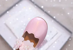 Detail von rosa glitzernden Prinzessinnenschuhen mit Chiffonblumen und Perlen
