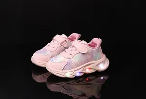 Detail of pink girls sports sneakers with magic tape and colorful LED glowing soles