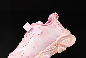 Detail of pink girls' sneaker with butterfly print and LED glowing lights on thick sole